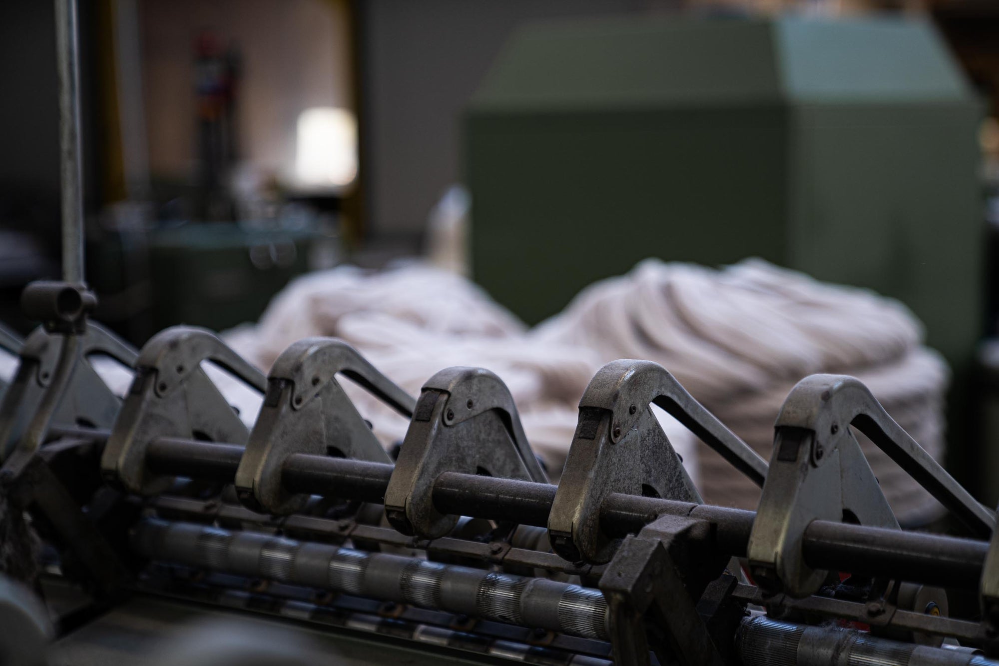 A close-up of a spinning frame at the ARA spinning facility, with combed wool tops in the background.