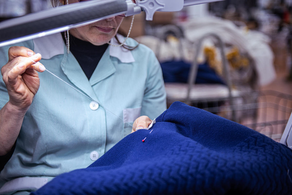 "A seamstress attaching a UNBORN brand label to the Merino d'Arles padded vest.