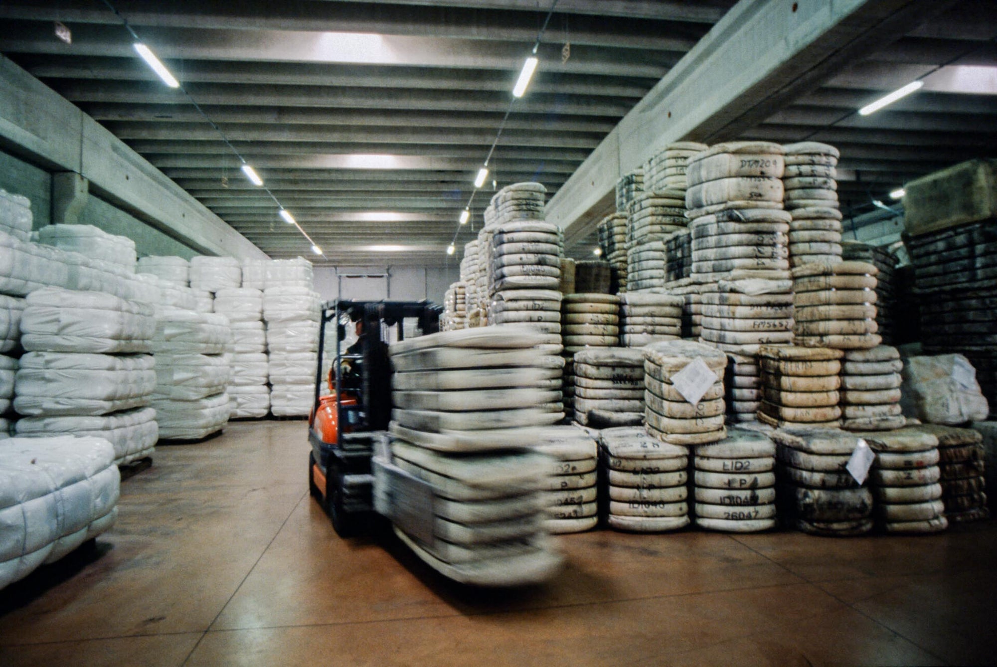 Forklift driver transporting bales of wool in the warehouse of Pettinatura di Verrone, filled with bales