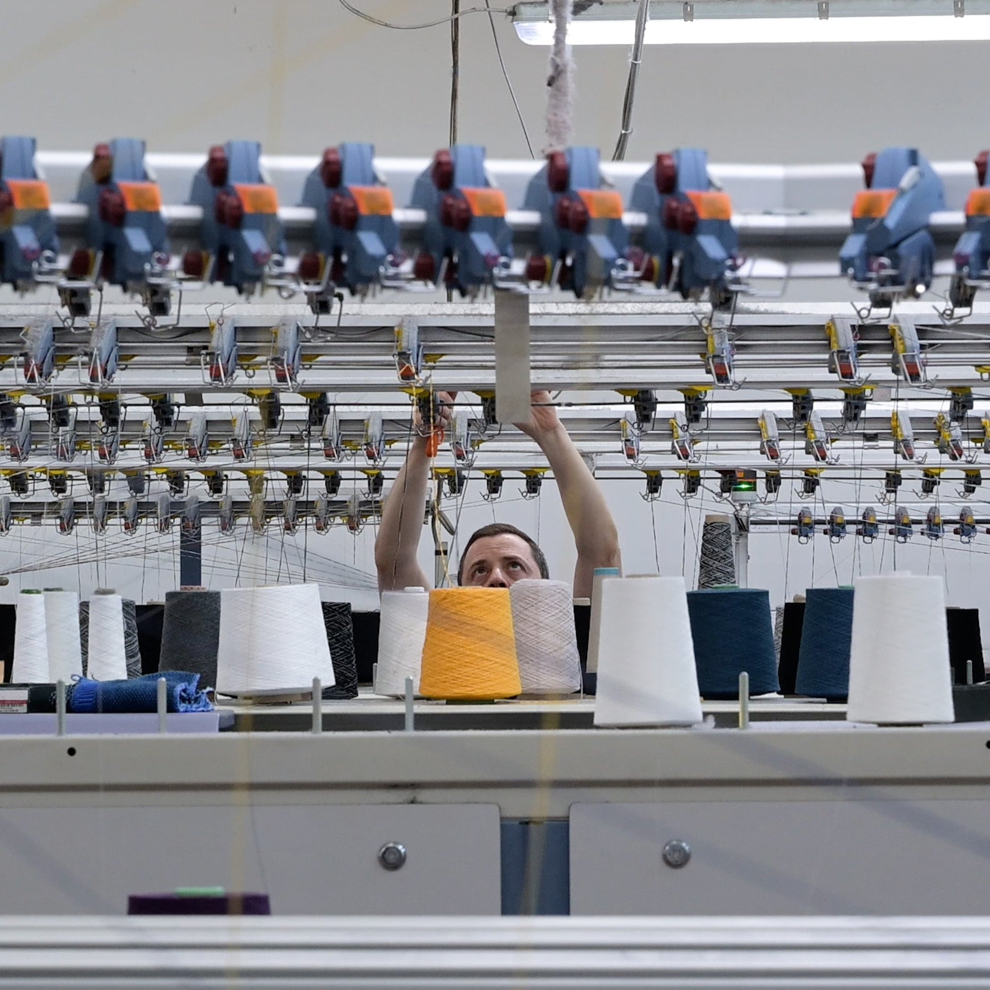 A technician operating a flatbed knitting machine at Point Tricot.