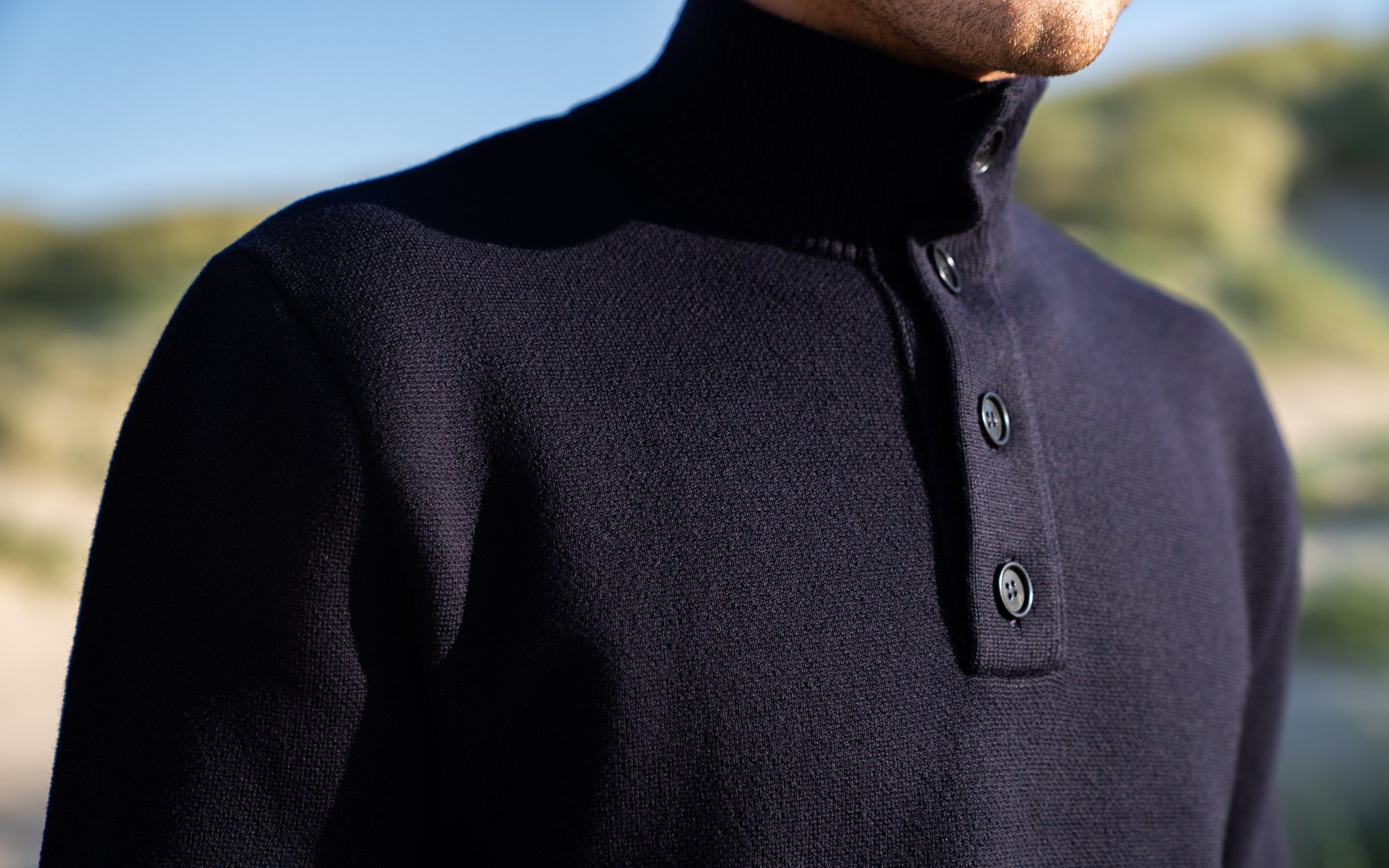 Close-up  of model wearing The Merino Jacquard Button Up in an outdoor dune area