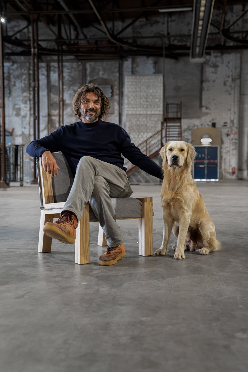 Melle Koot sitting on the Herbarium Lounge chair with his Labrador sitting on the side