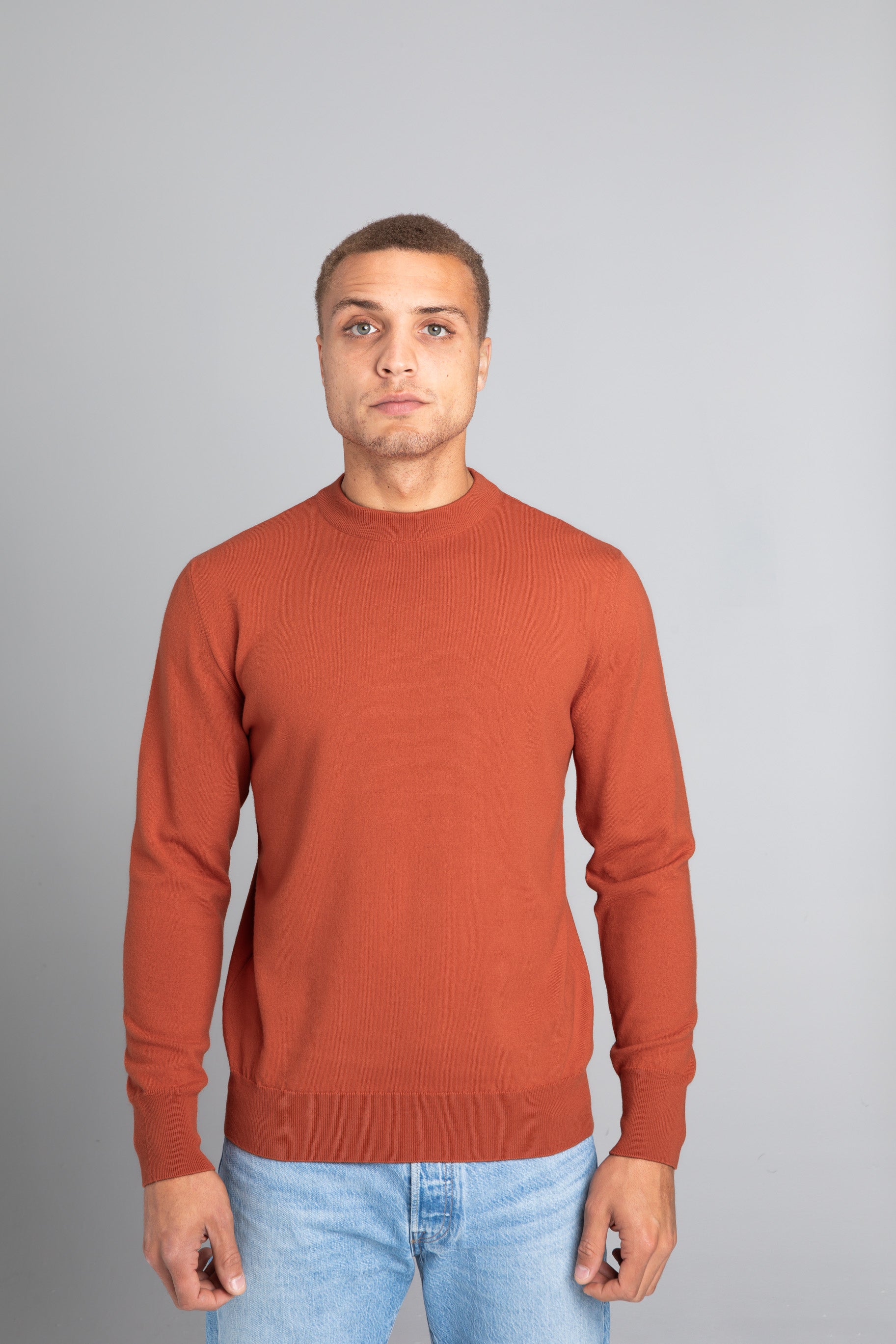 Model wearing The Merino Sweater lightweight Burnt Orange, front view - Unborn
