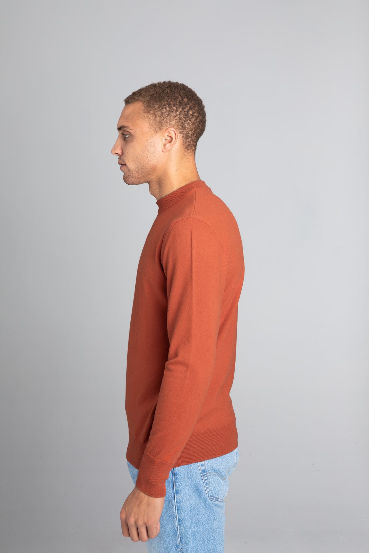 Model wearing The Merino Sweater lightweight Burnt Orange, left view - Unborn
