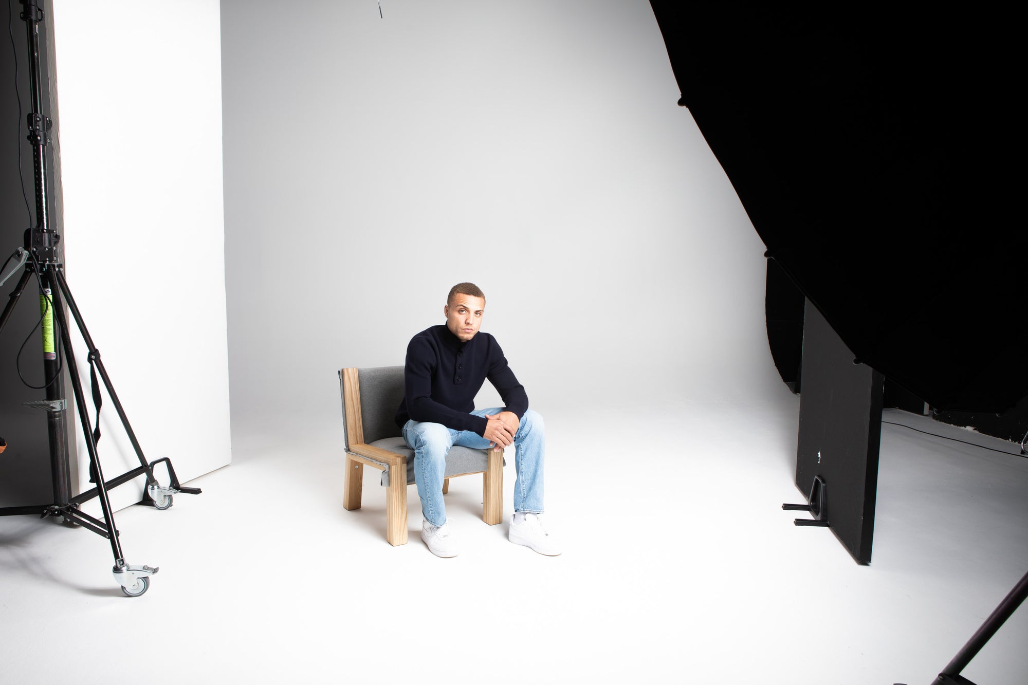 Model Wearing Heavy Merino Sweater Navy Sitting Chair Studio