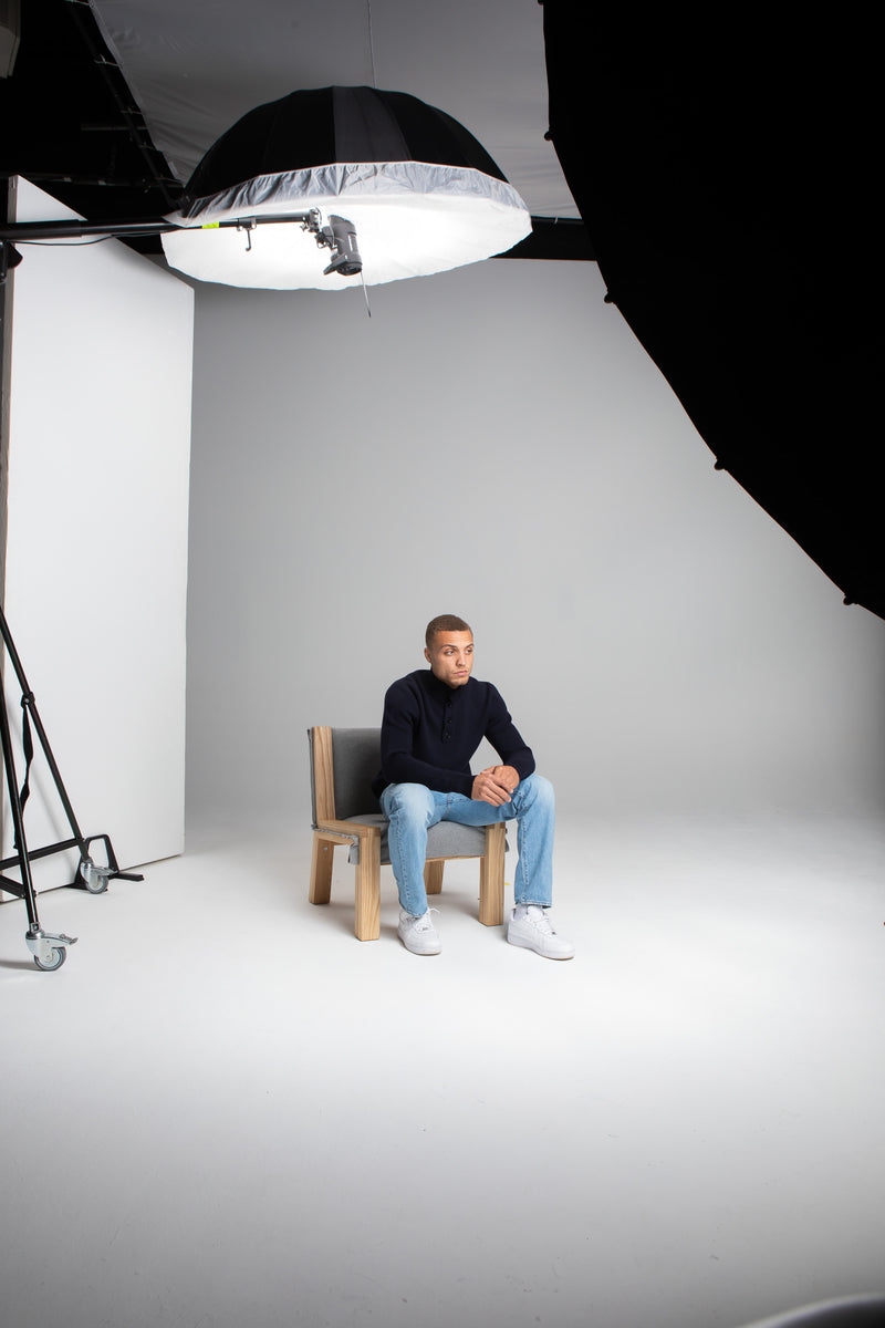 Model Wearing Heavy Merino Sweater Navy Sitting Chair Studio