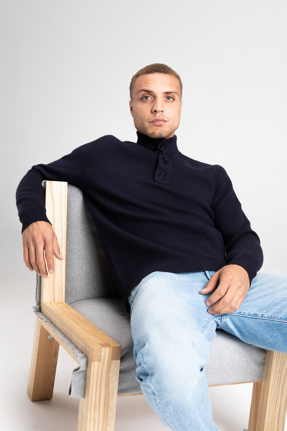 Model Wearing Heavy Merino Sweater Navy Sitting Chair Studio