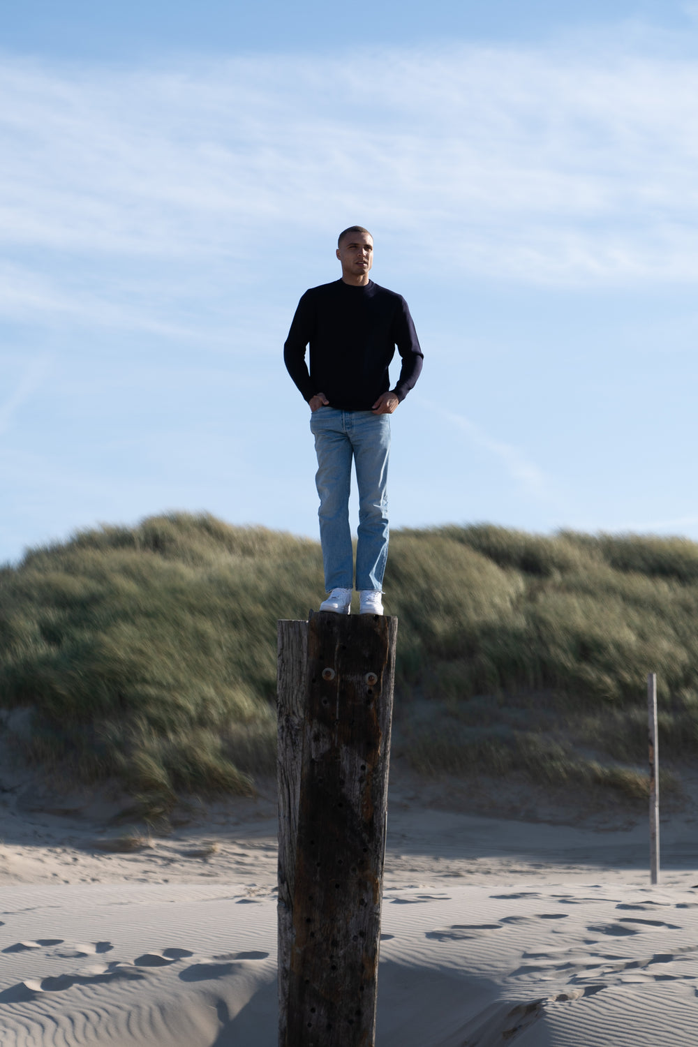 Model Wearing Heavy Merino Sweater Standing Pillar Beach
