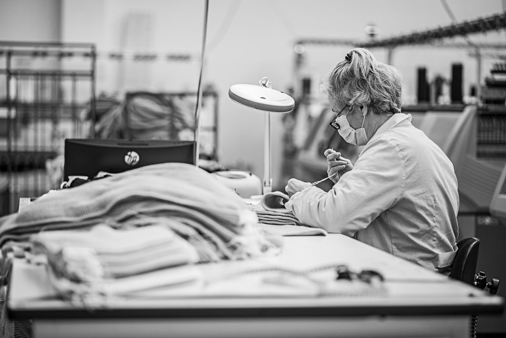 Artisan seamstress of Point Tricot sewing the garment lables to unborn sweaters