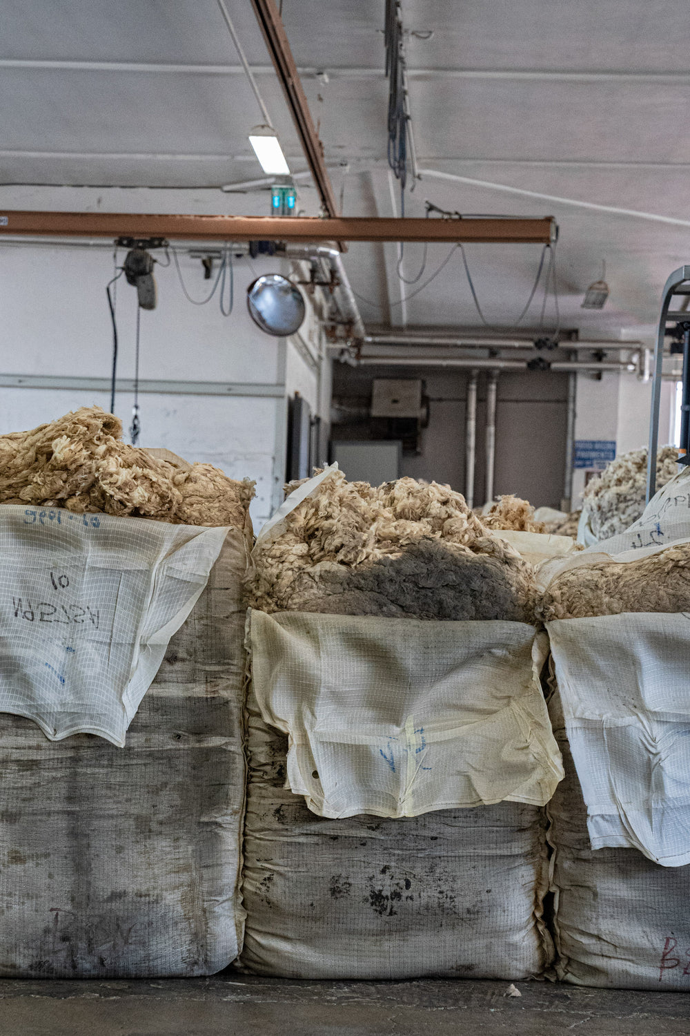 Opened Bales filled with Merino wool fleeces resting at Romagnano sesia