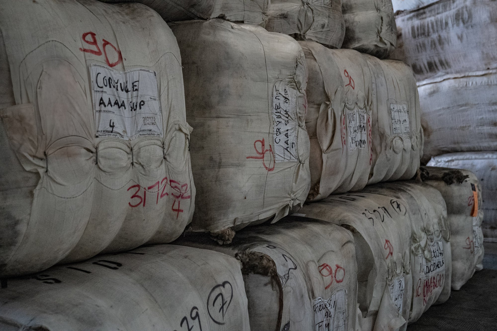 Bales filled with Merino wool fleeces stacked in warehouse at Romagnano sesia