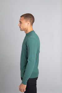 Model wearing The Merino Wool Sweater Light Foggy Green , left - Unborn