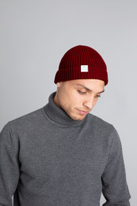 Model wearing The Merino wool beanie  brick red, front view Unborn