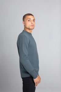 Model wearing The Merino Wool Sweater Olive Green, right - Unborn